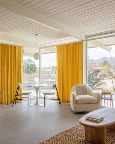 Yellow curtains framing the desert garden and boulders